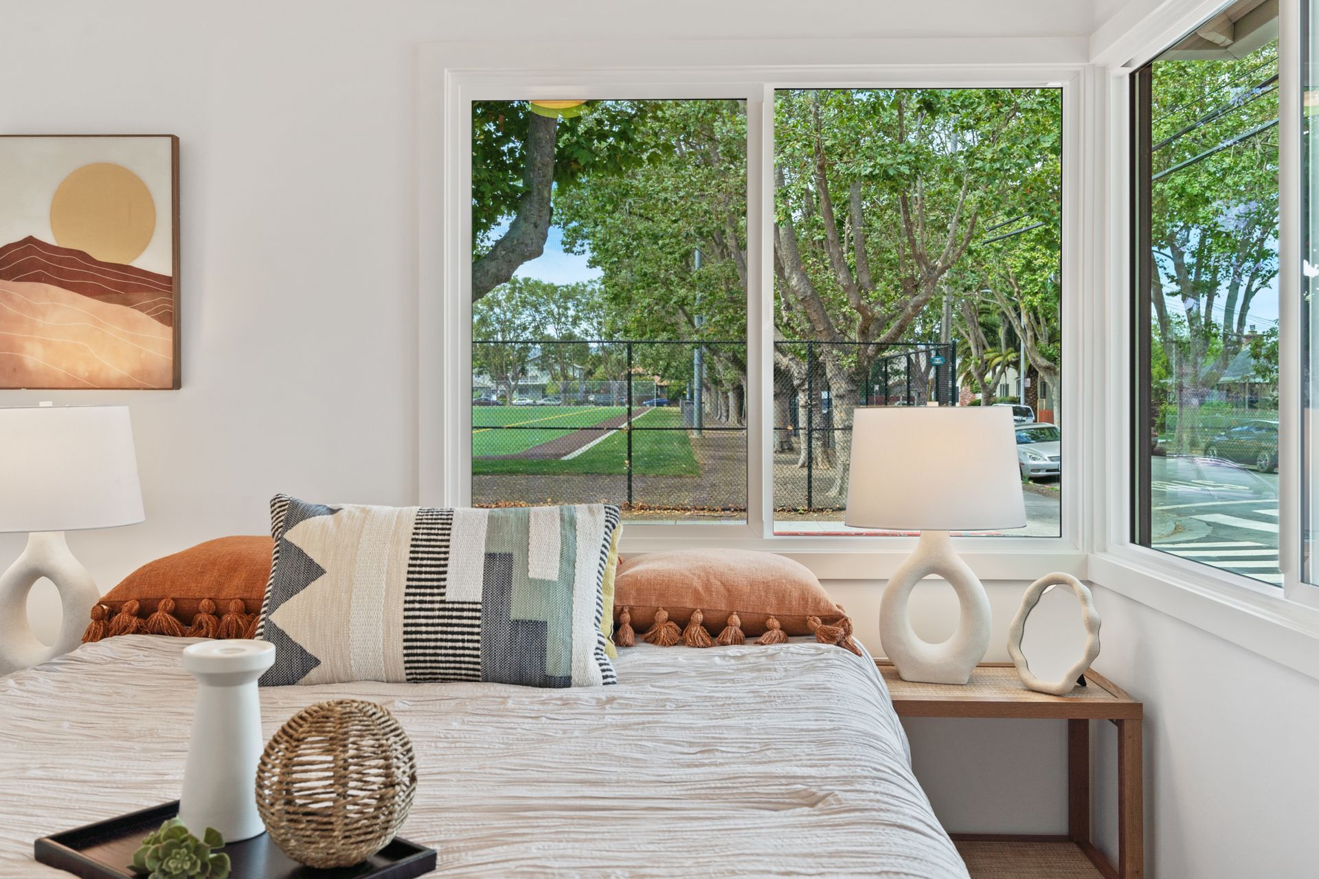 A bedroom with a bed , lamps , and a large window.