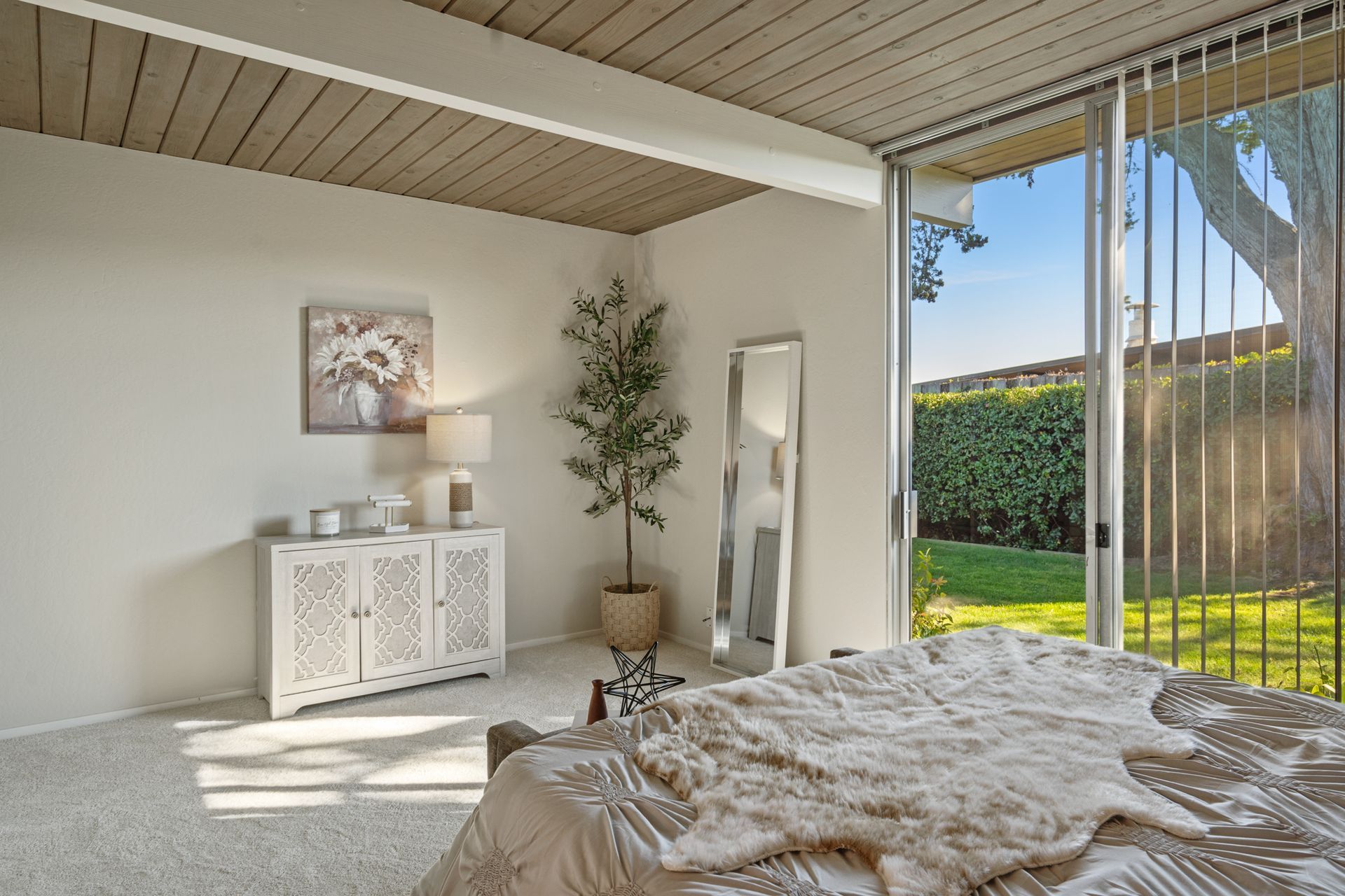 A bedroom with a bed , dresser , mirror and sliding glass doors.