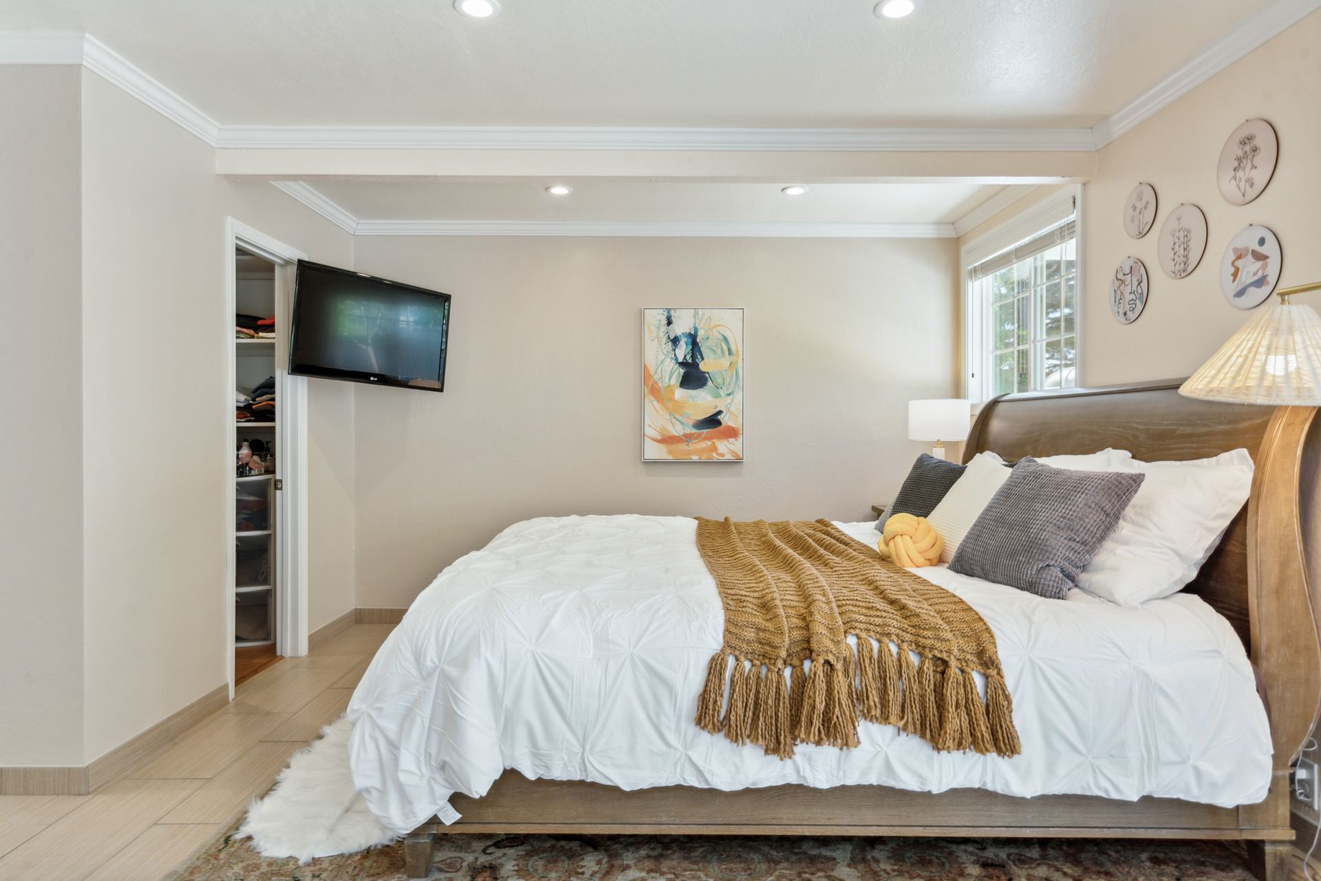 A bedroom with a large bed and a flat screen tv on the wall.