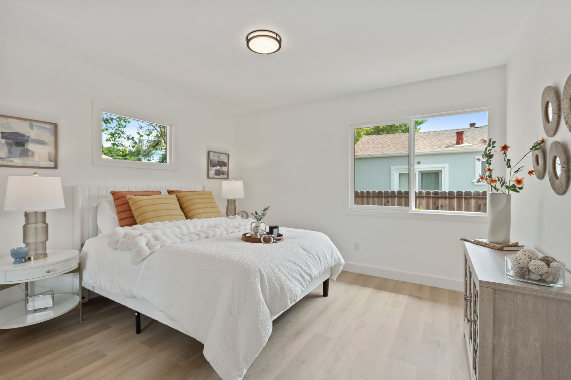 A bedroom with a bed , dresser , nightstand and two windows.