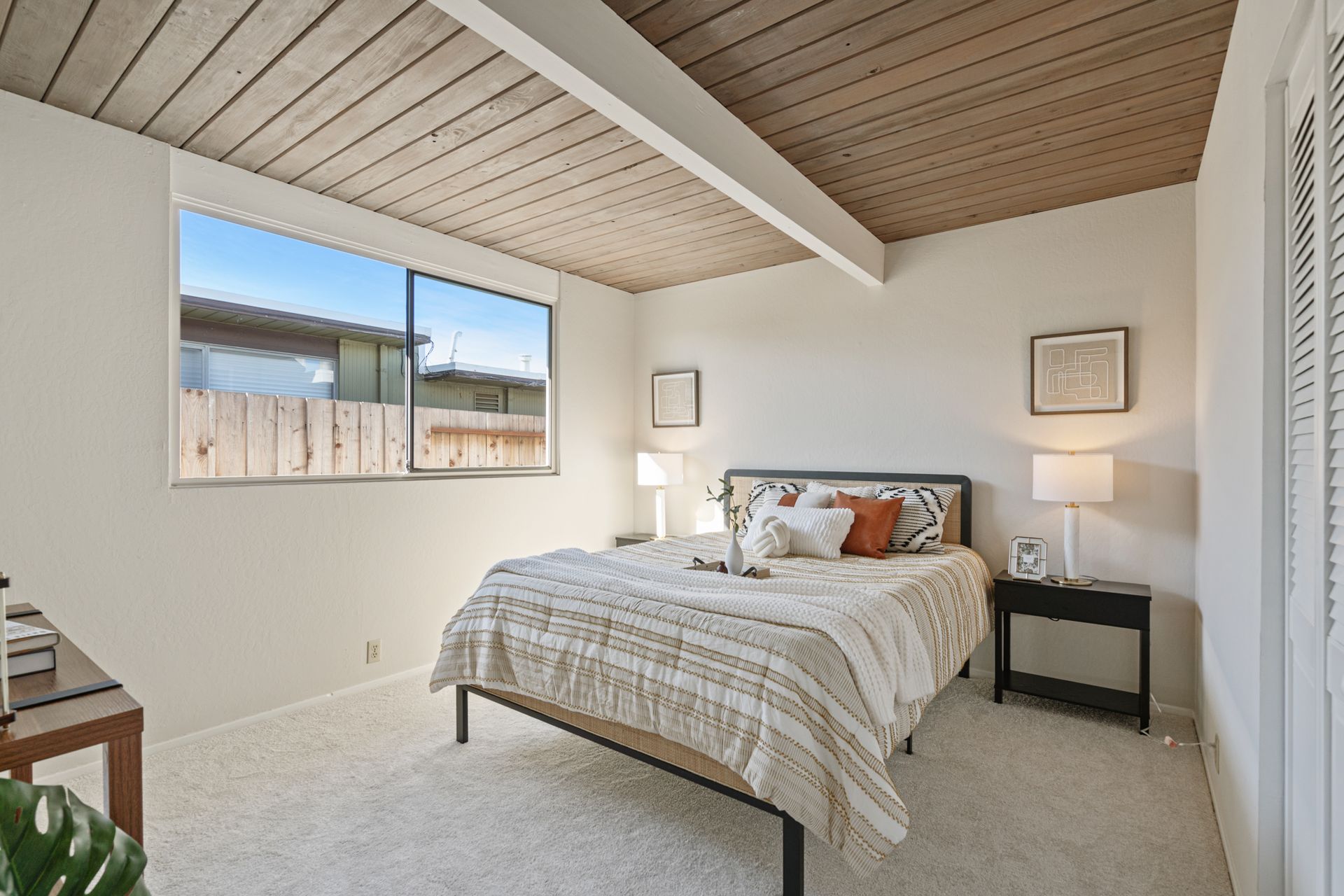 A bedroom with a bed , nightstand , lamps and a window.