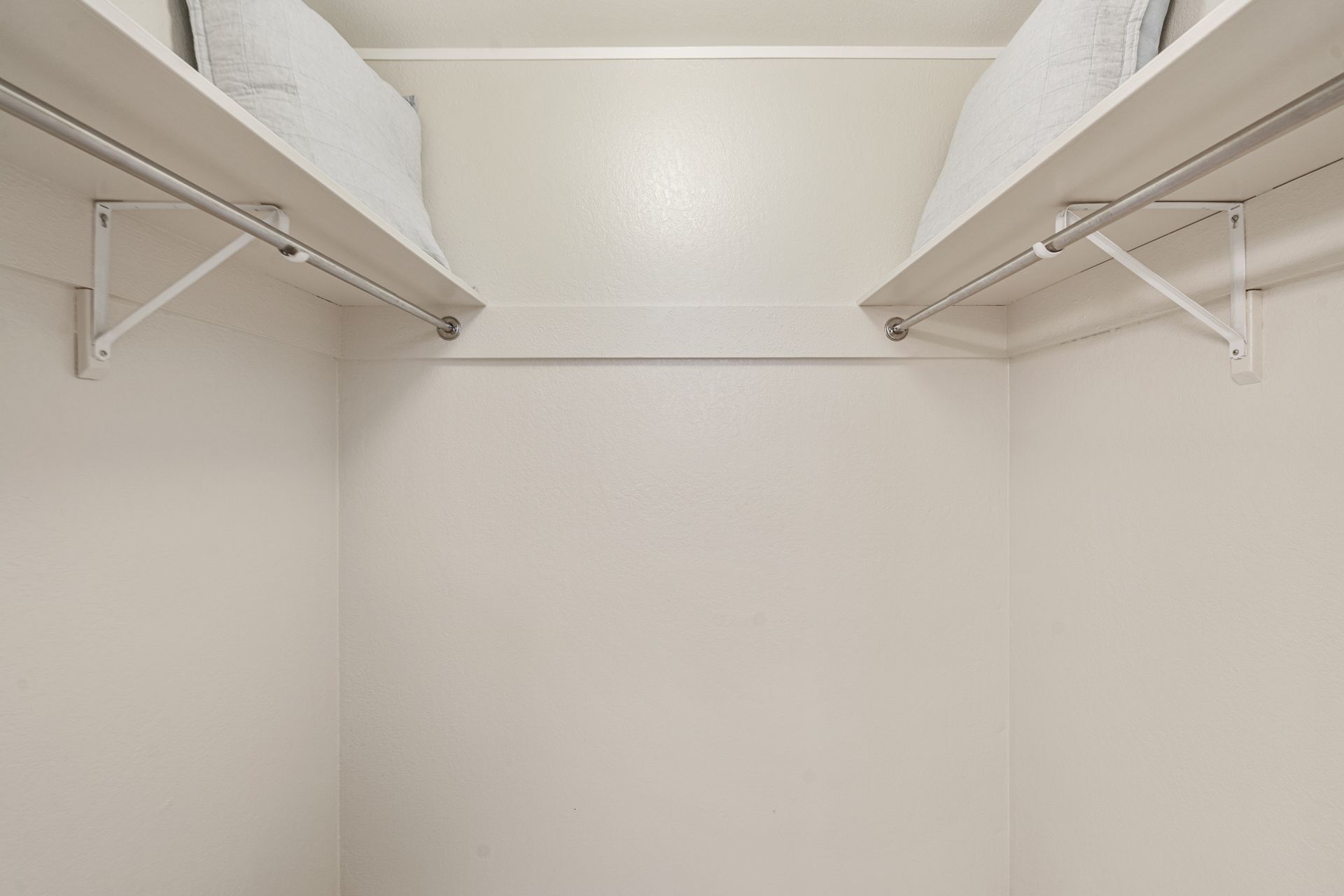 A walk in closet with two shelves and a ceiling.