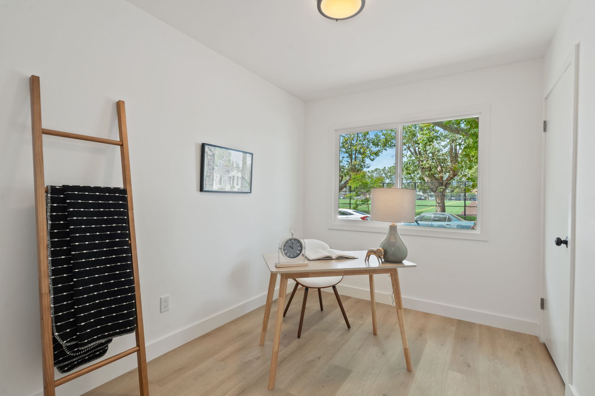 A room with a desk , chair , lamp and window.