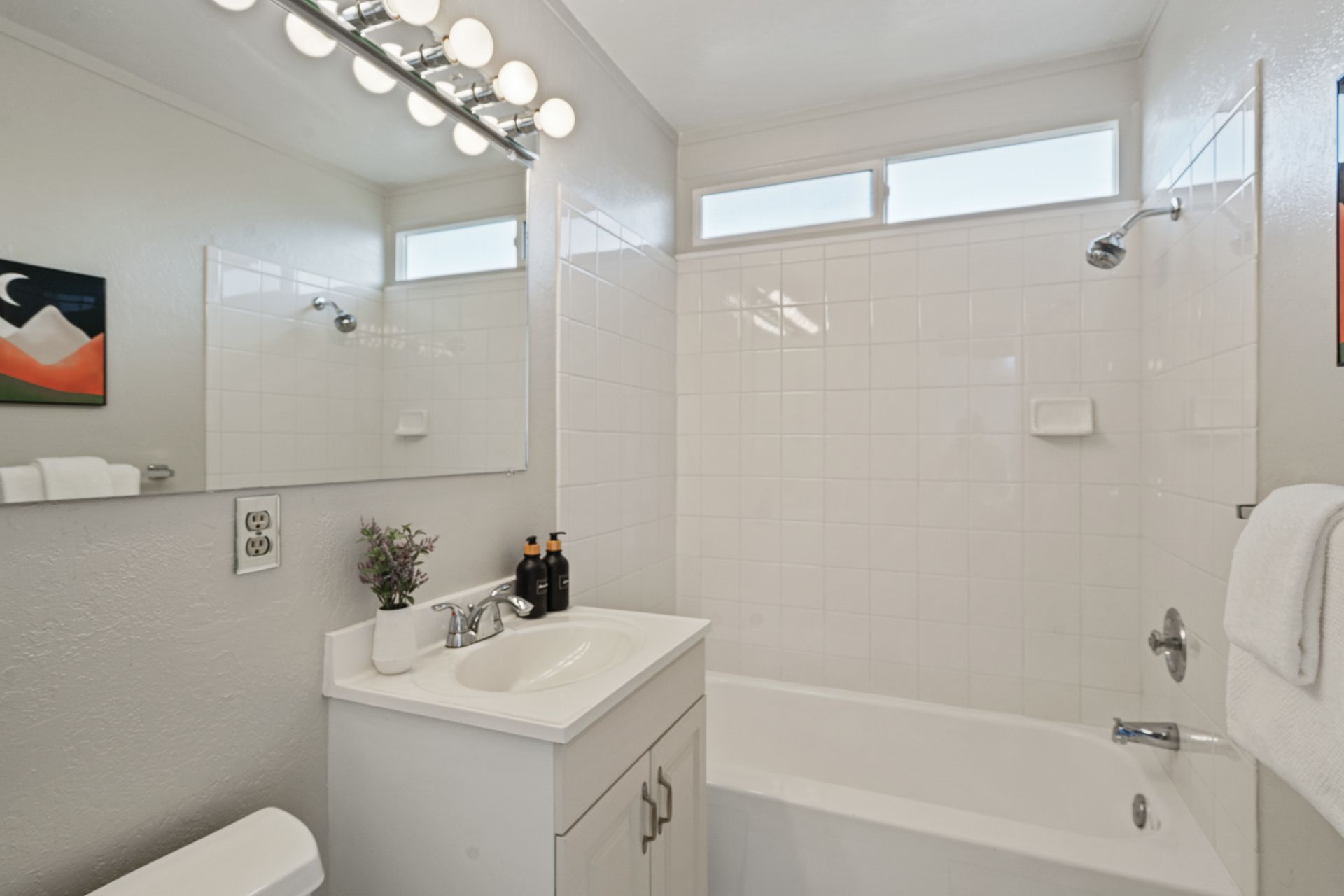 A bathroom with a sink , toilet , tub and mirror.