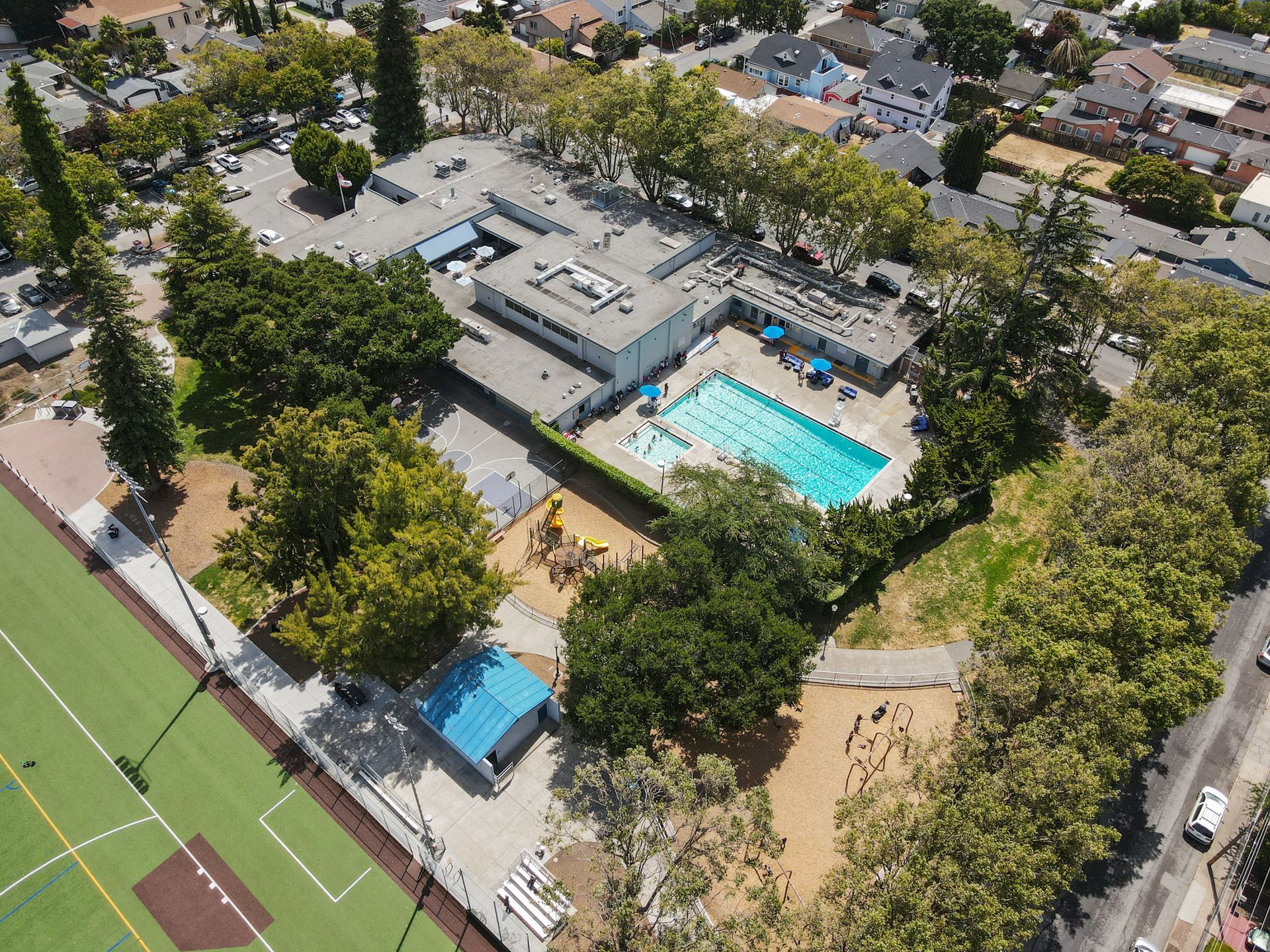 An aerial view of a park with a swimming pool and a baseball field.