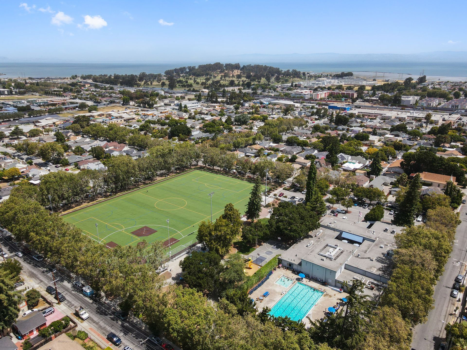 An aerial view of a city with a baseball field and a swimming pool.