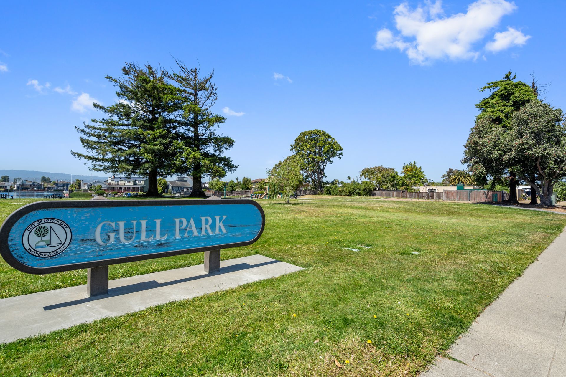 A sign for gull park is sitting in the middle of a grassy field.