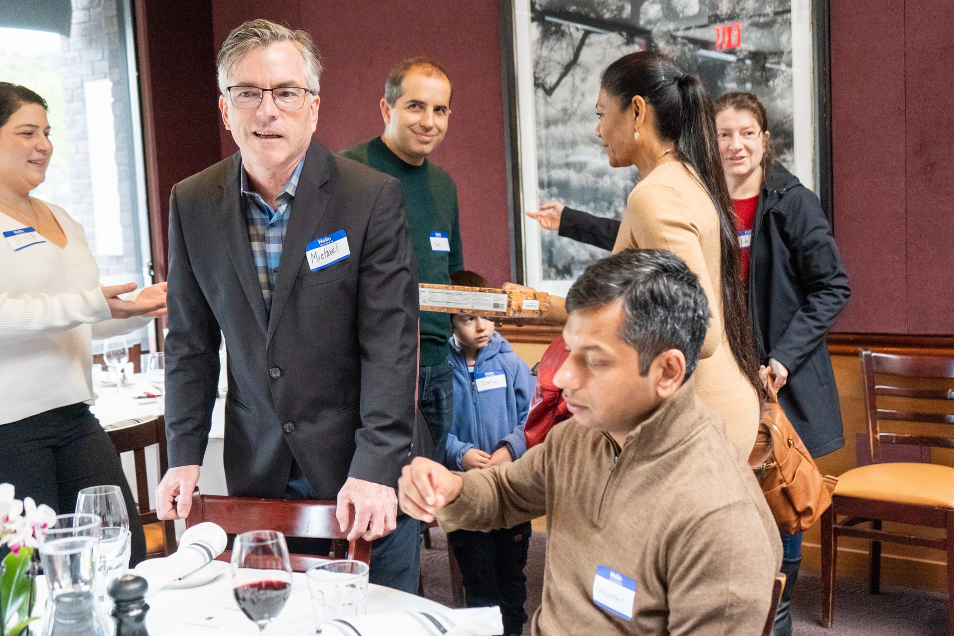 A group of people are sitting at a table in a restaurant shaking hands.