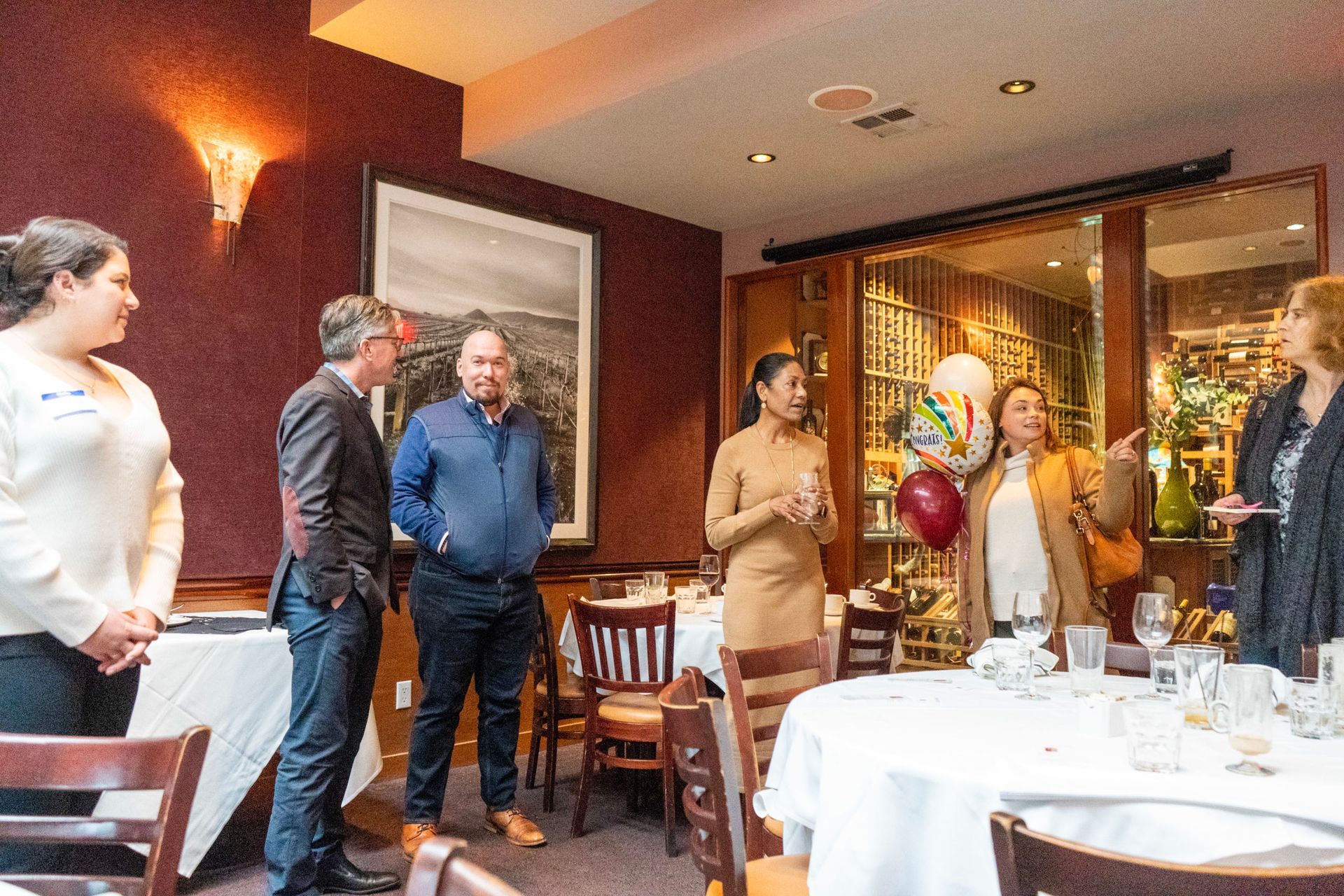 A group of people are standing around a table in a restaurant.