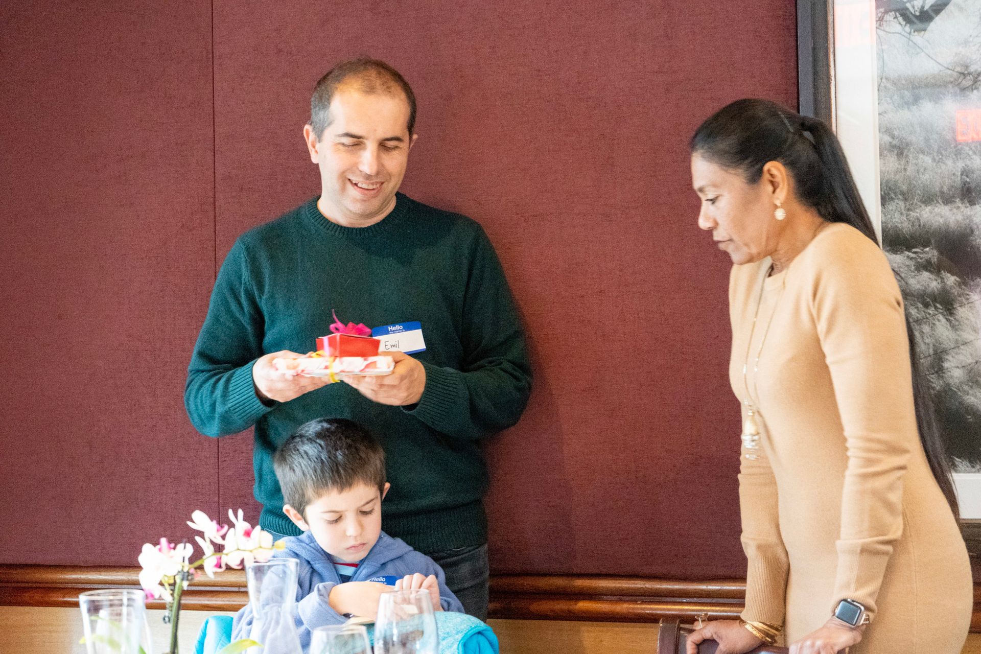 A man and a woman are standing next to a child at a table.