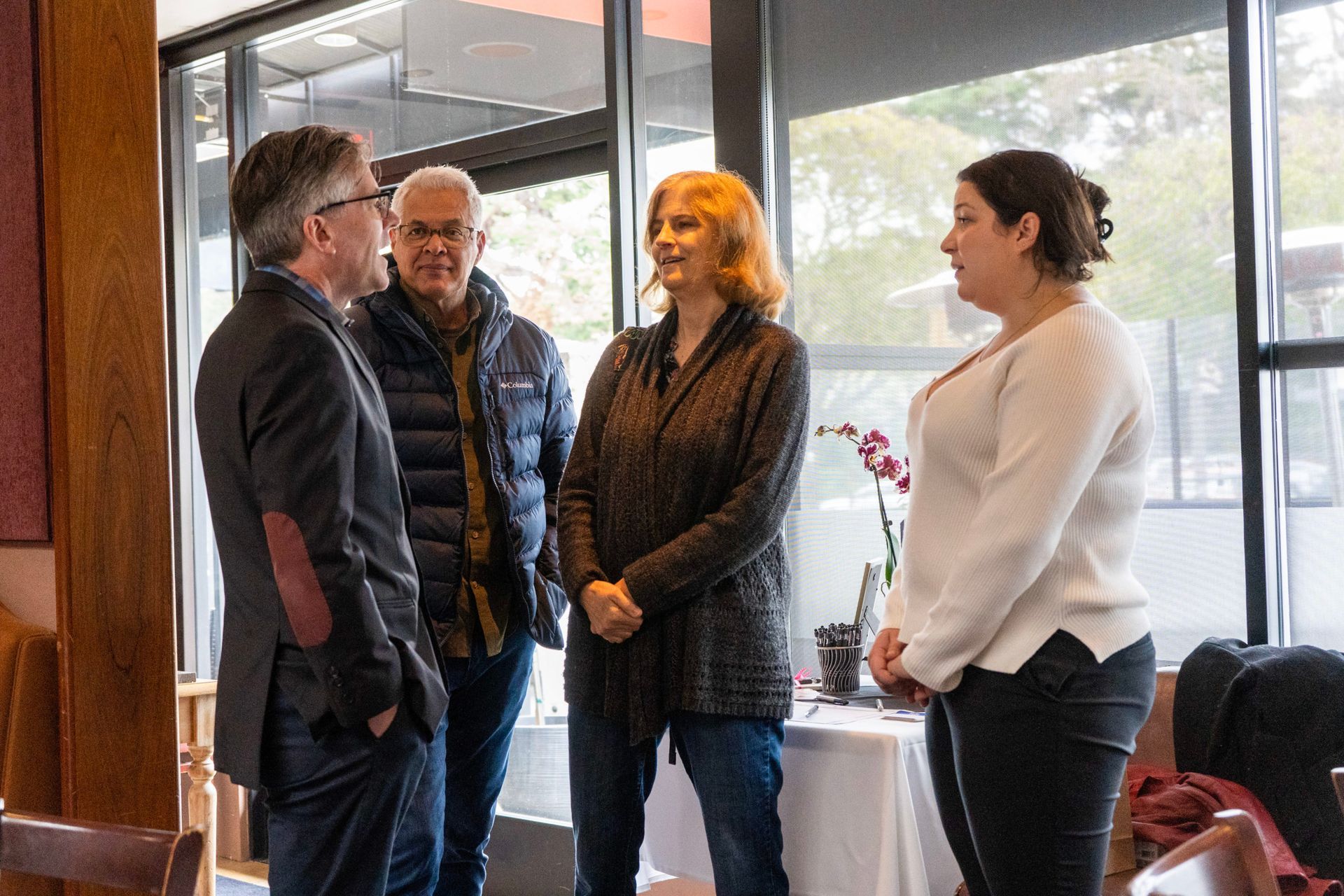 A group of people are standing in a room talking to each other.
