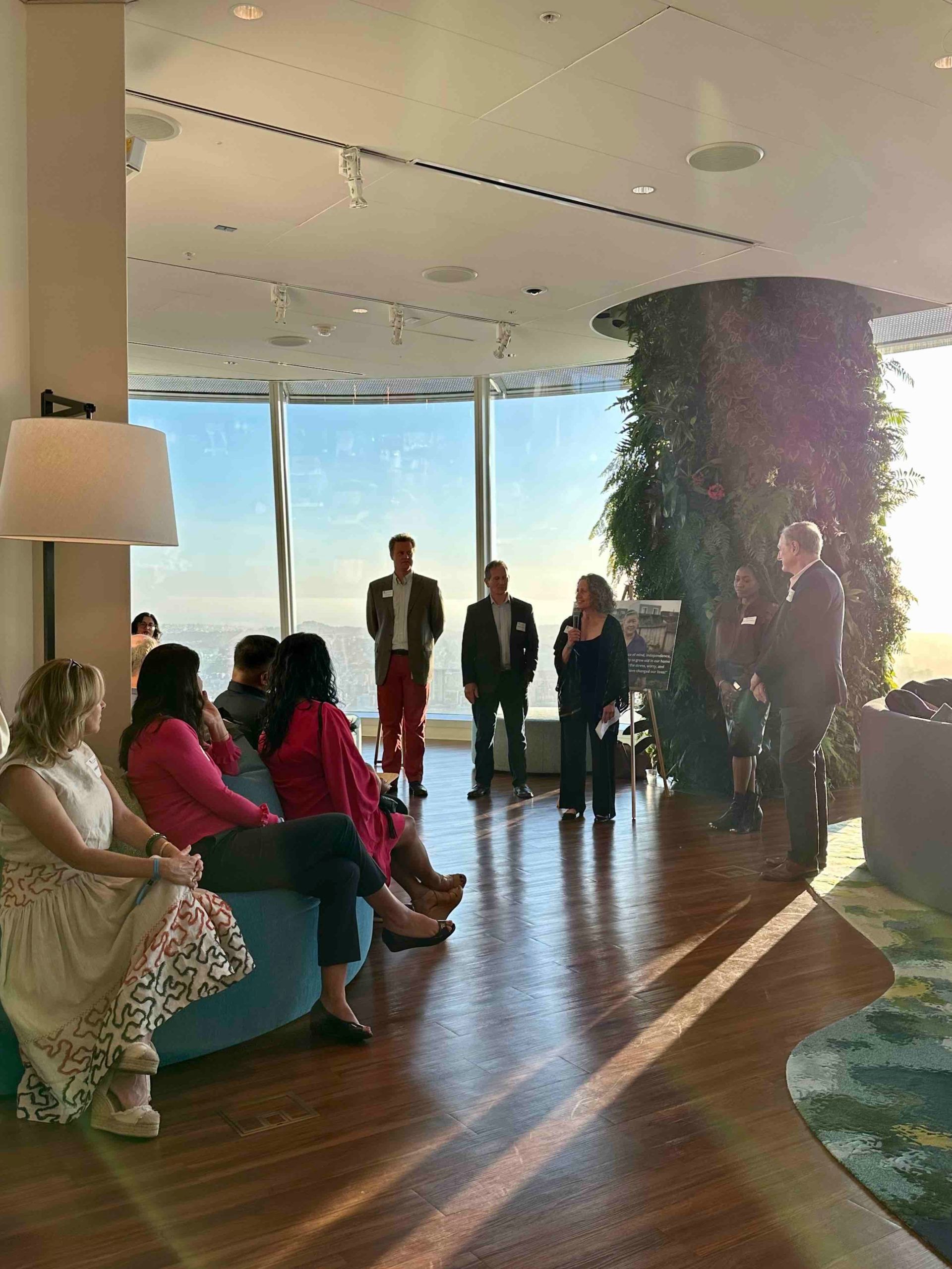 A group of people are sitting in a room with a large window.
