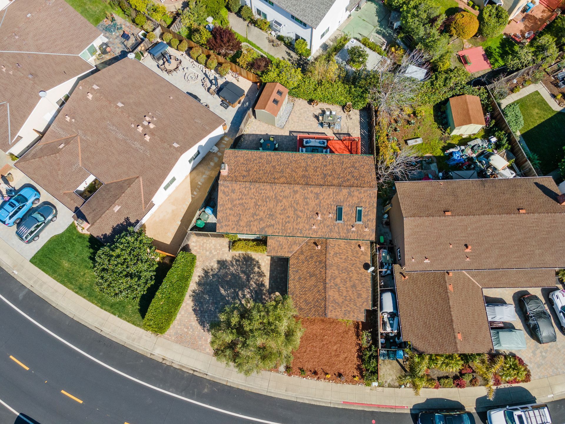 An aerial view of a residential area with houses and cars parked on the side of the road.