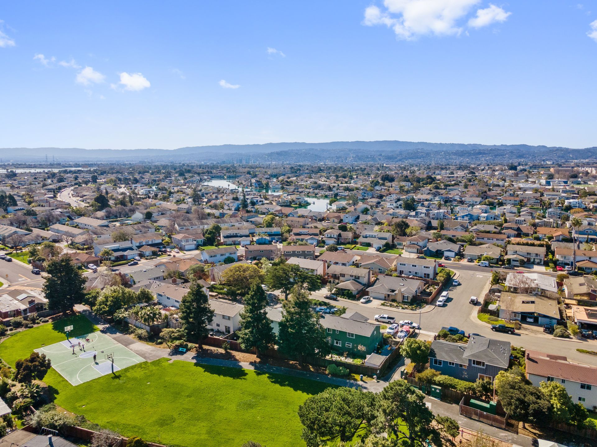 An aerial view of a residential area with a tennis court in the middle.