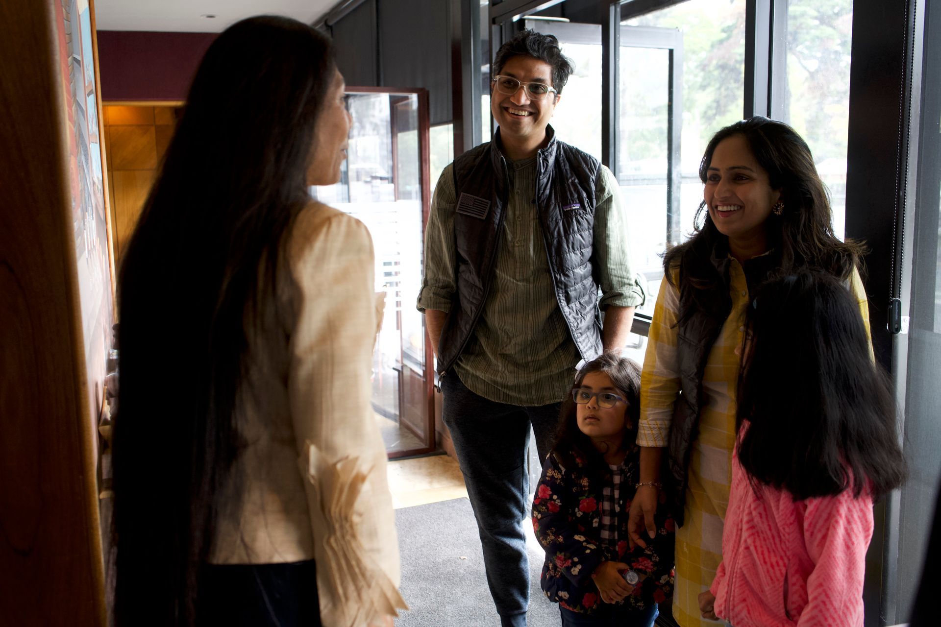 A group of people are standing in a hallway talking to each other.