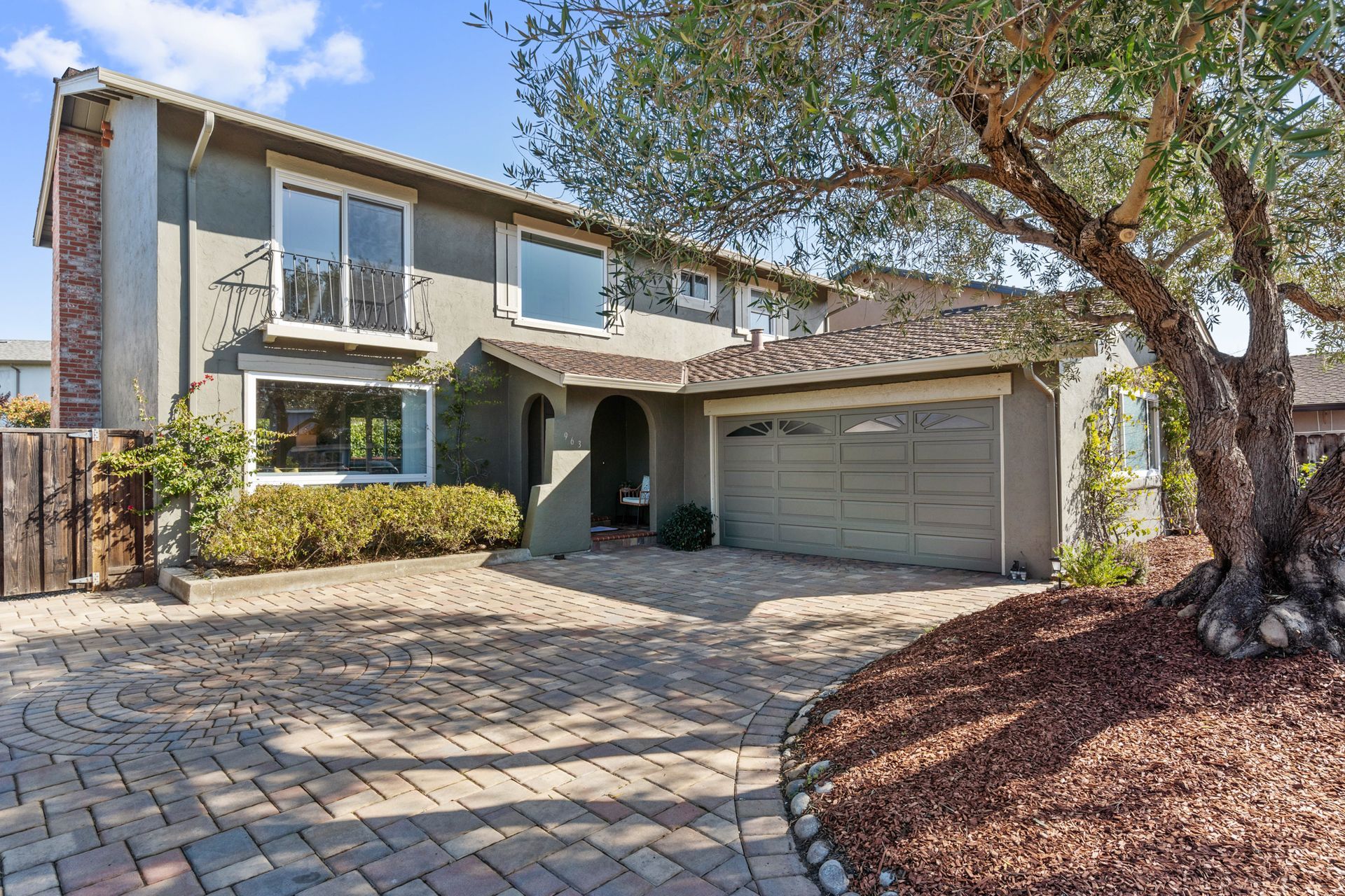 A large house with a garage and a tree in front of it.