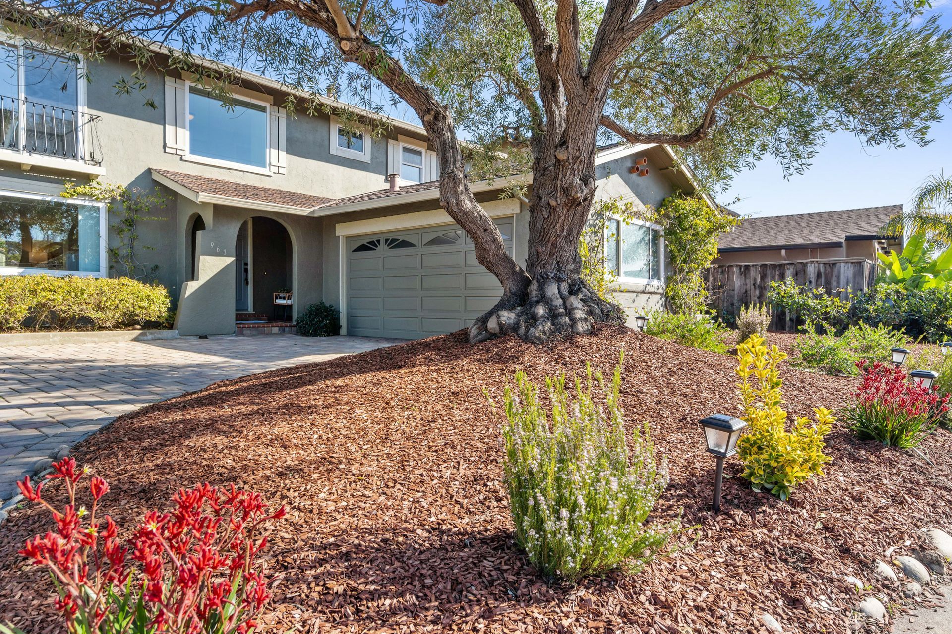 A house with a tree in front of it and a lot of mulch.