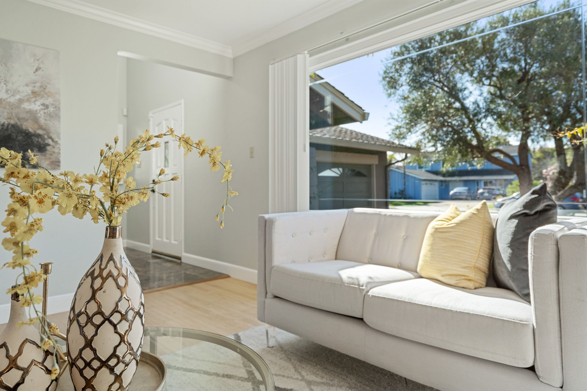 A living room with a white couch and a glass coffee table.