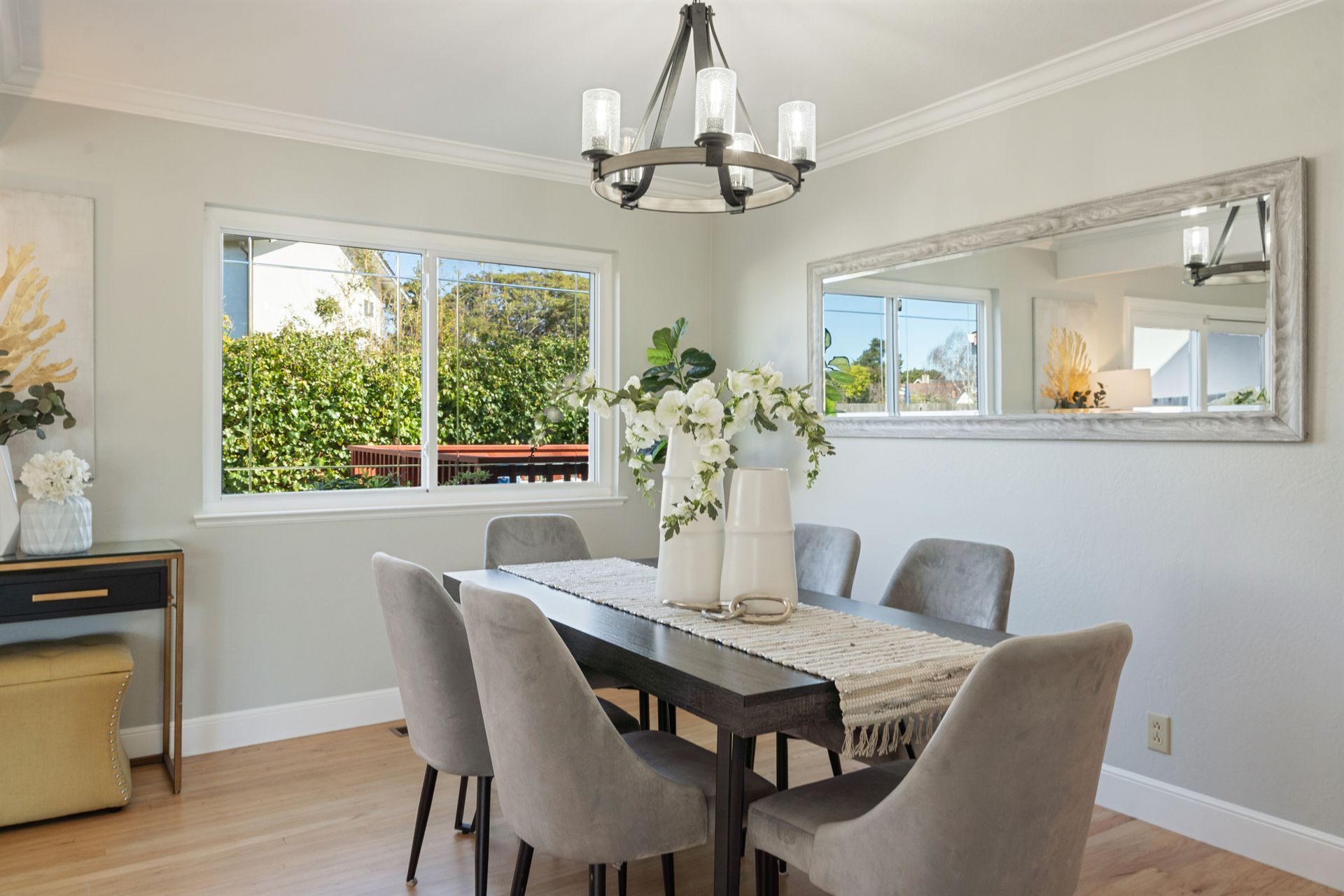 A dining room with a table and chairs and a large mirror.