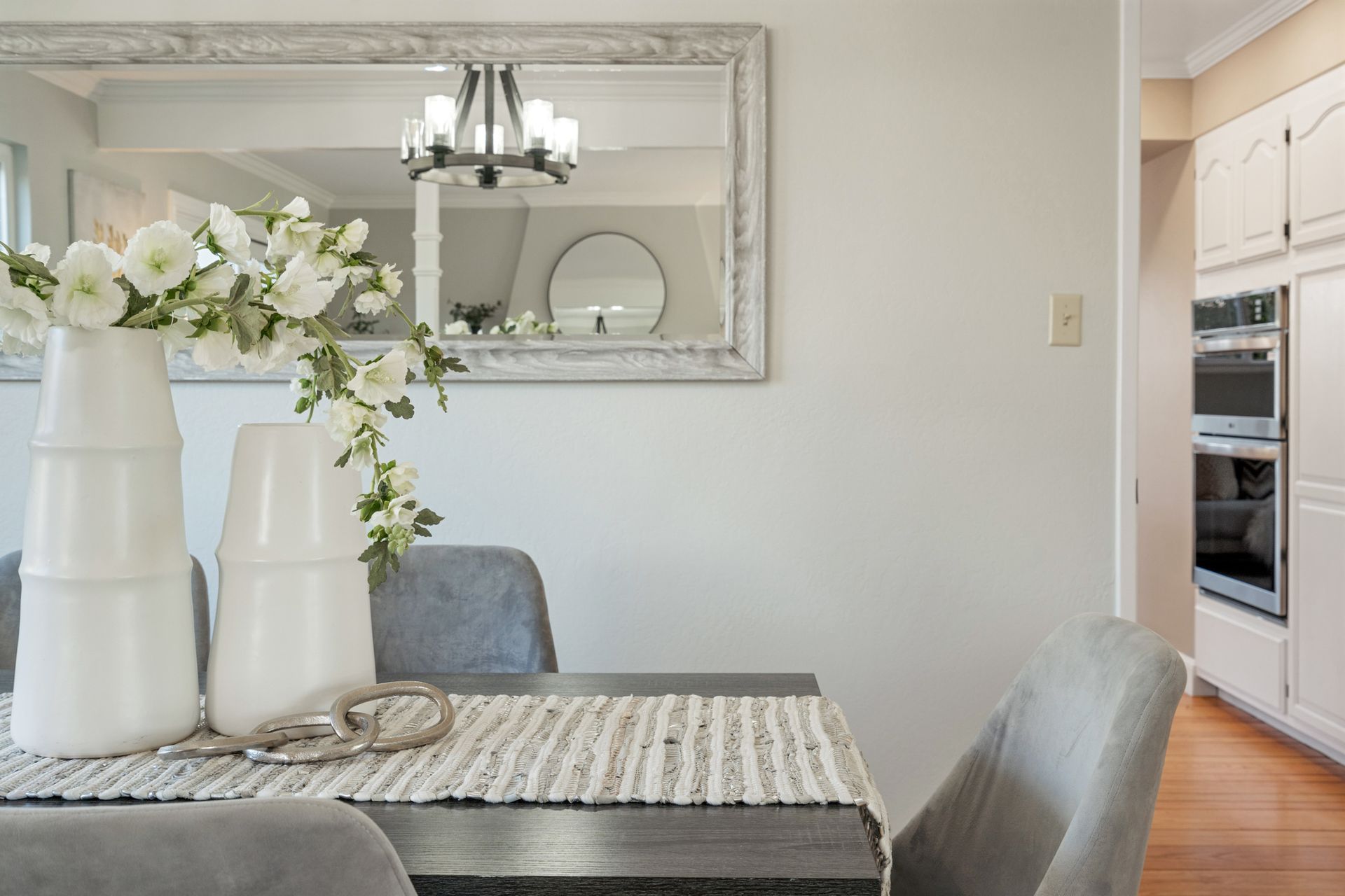 A dining room table with two vases of flowers on it.