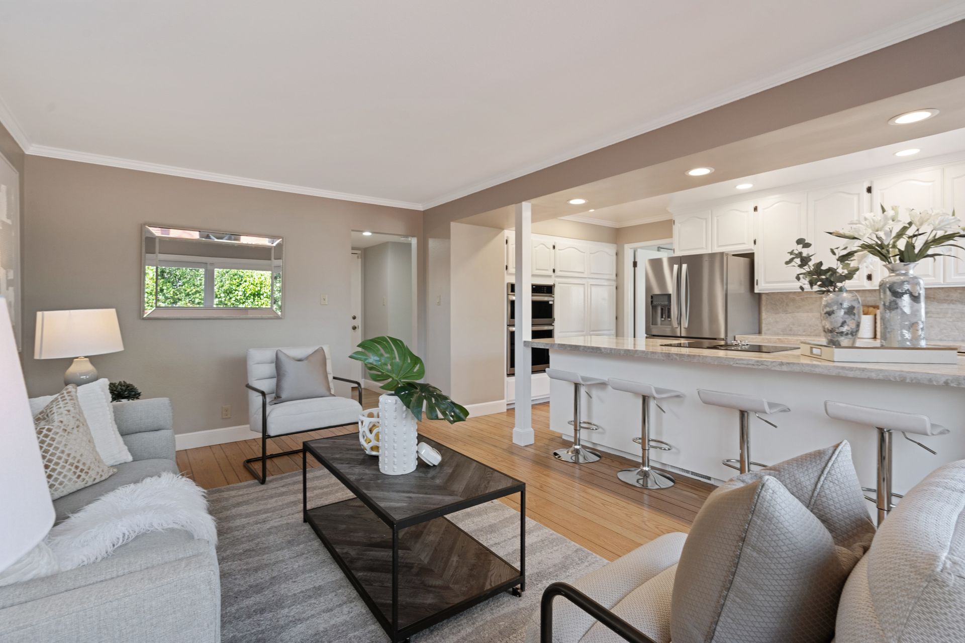 A living room with a couch , chair , coffee table and kitchen.