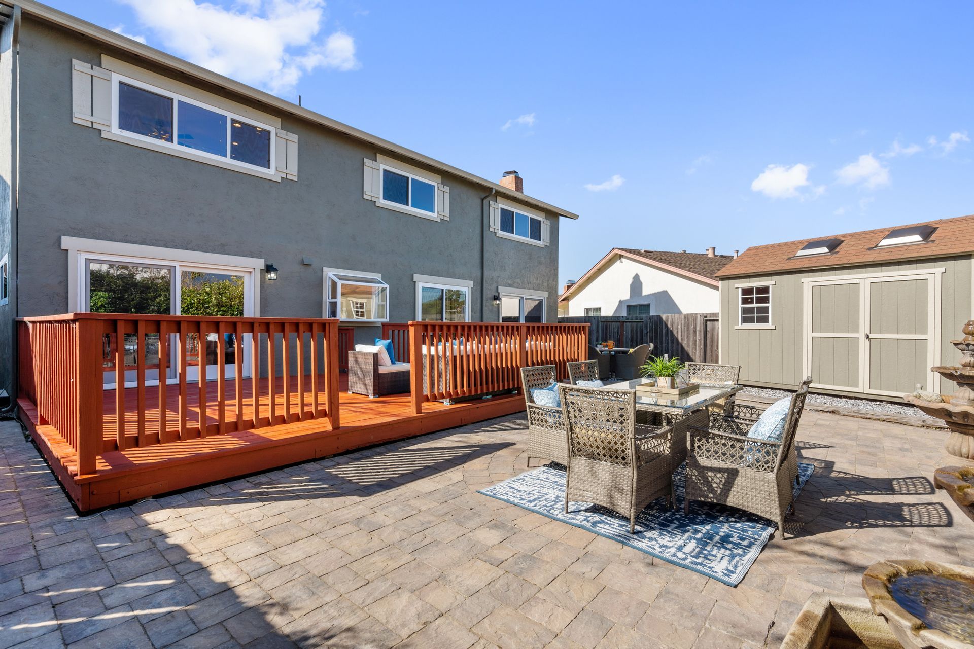 The backyard of a house with a large wooden deck and patio furniture.