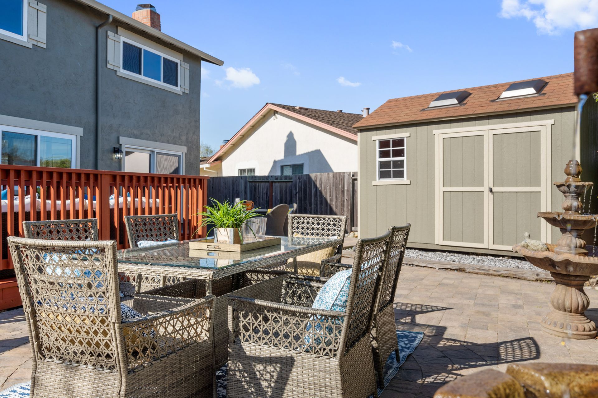 A patio with a table and chairs and a shed in the backyard.
