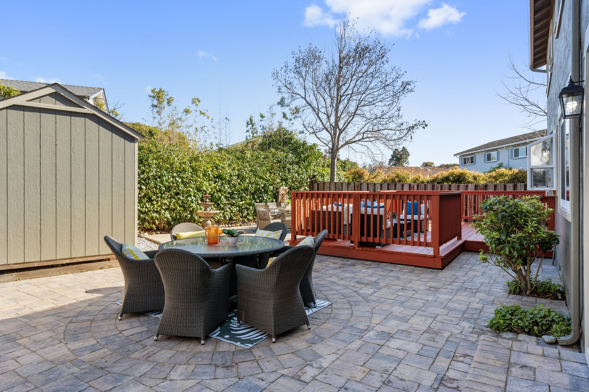 A patio with a table and chairs and a red deck.