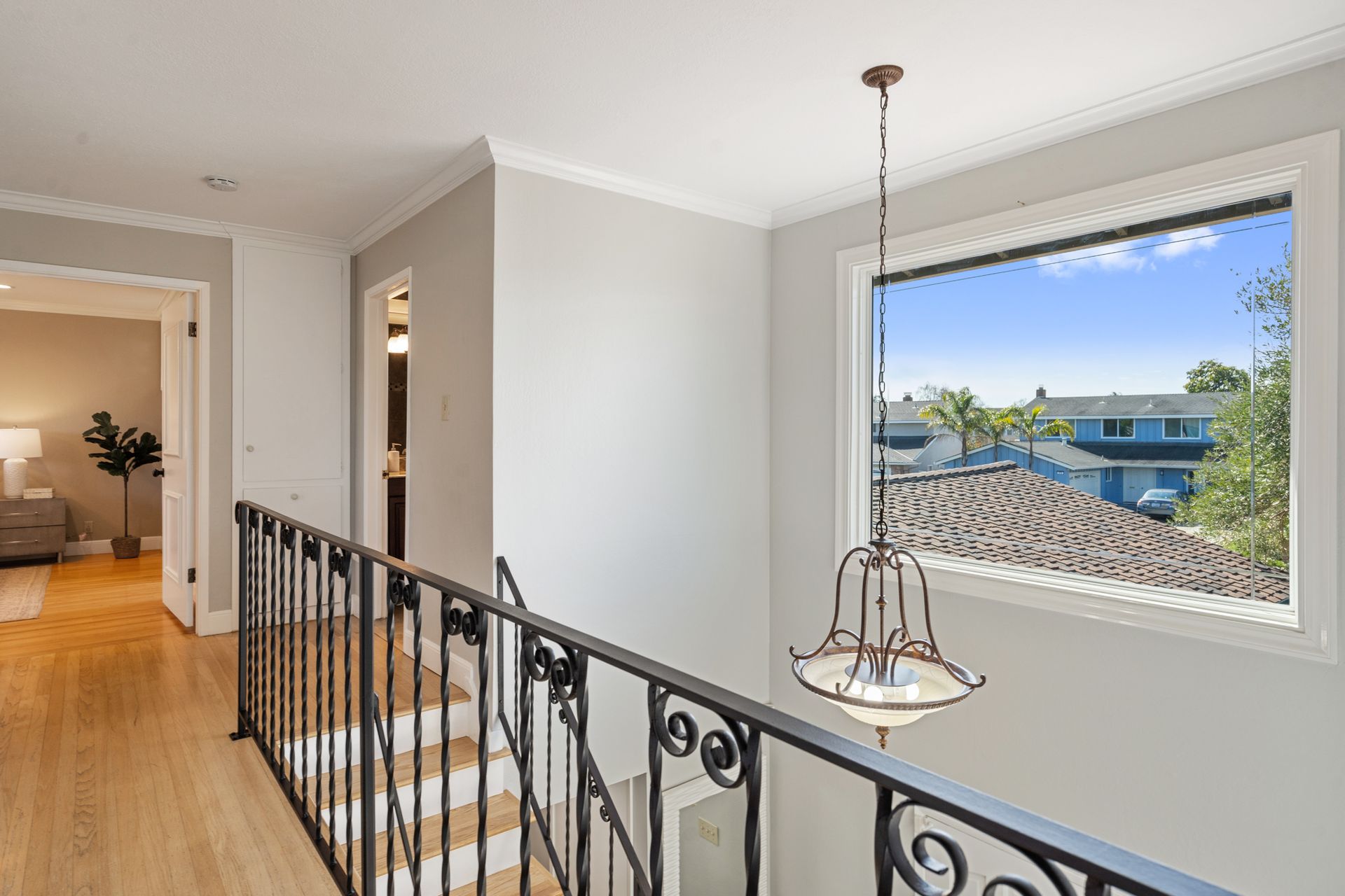 A hallway with stairs and a window with a view of a house.