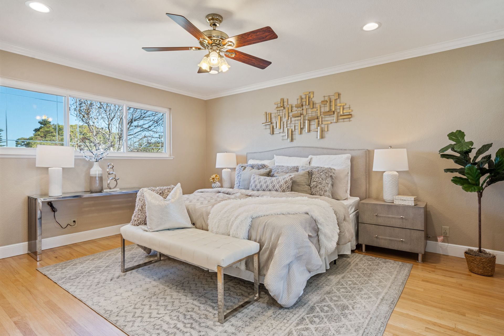 There is a ceiling fan in the bedroom with a large bed.