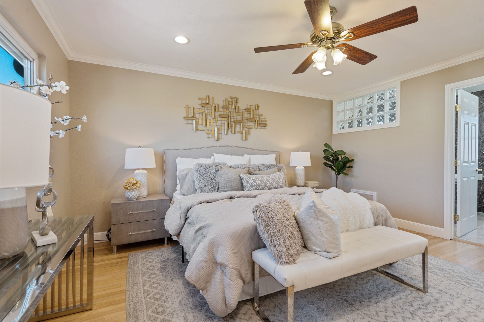 There is a ceiling fan in the bedroom with a large bed.