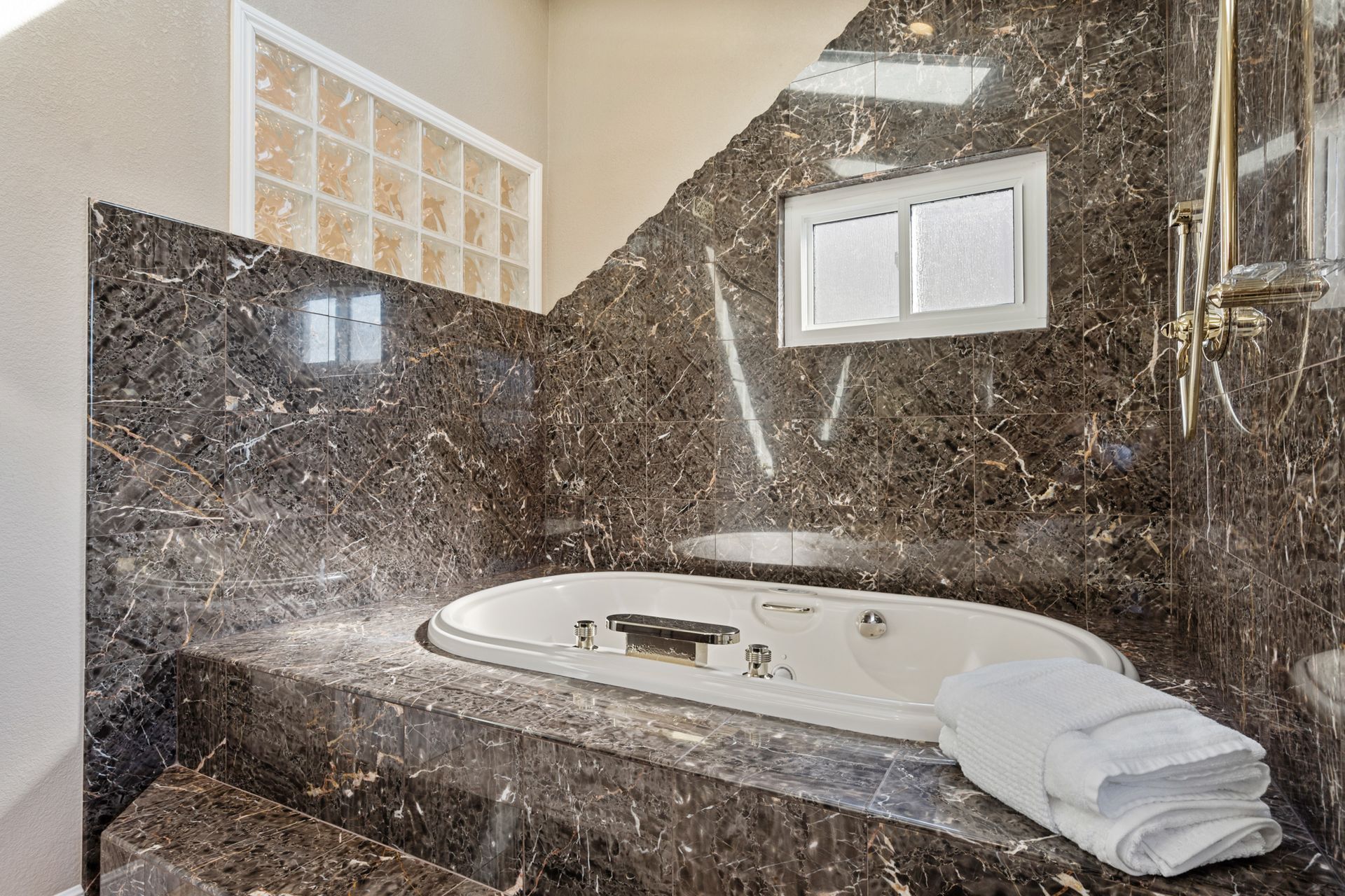 A bathroom with a jacuzzi tub and towels on the counter.
