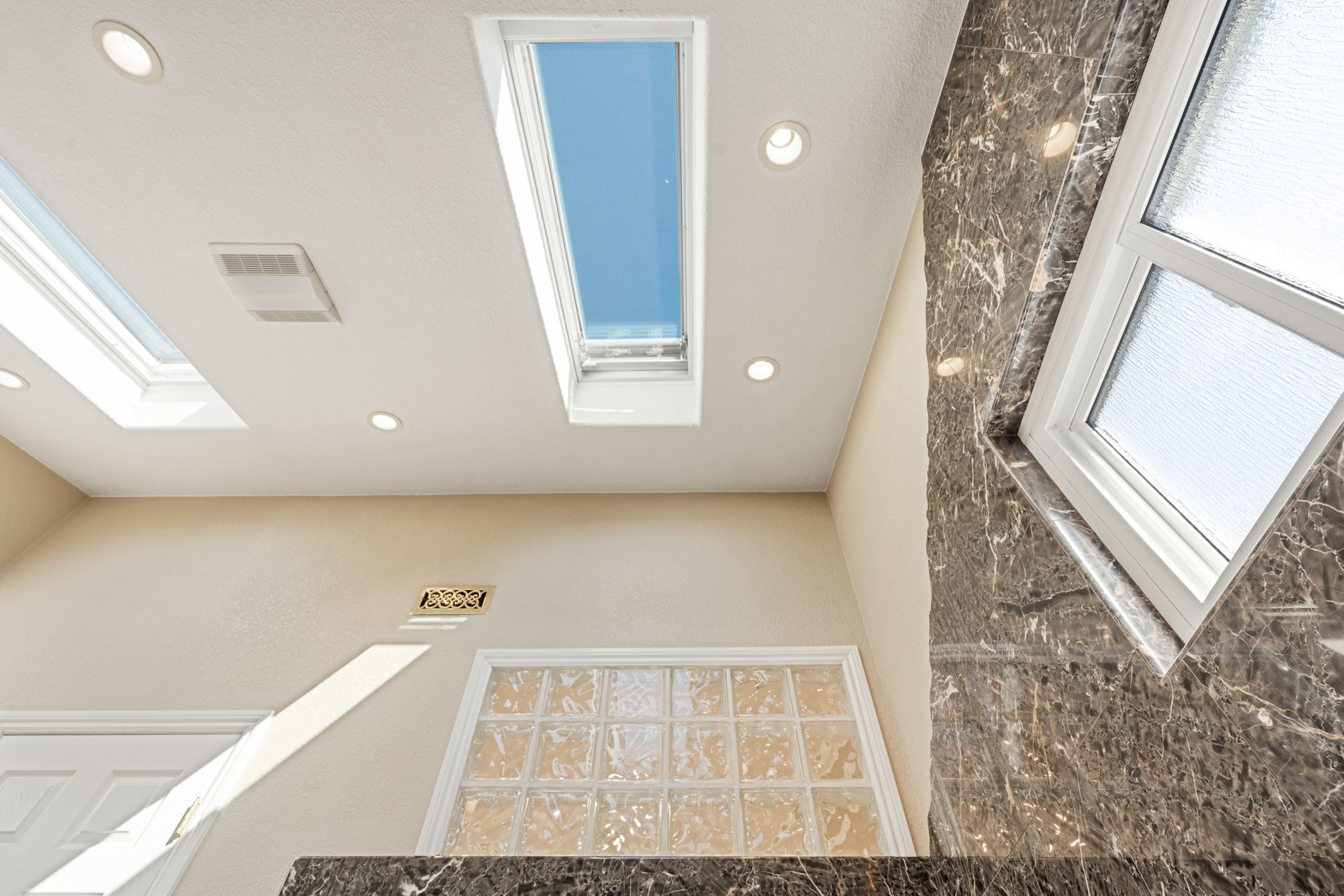 A bathroom with a skylight and a marble counter top.