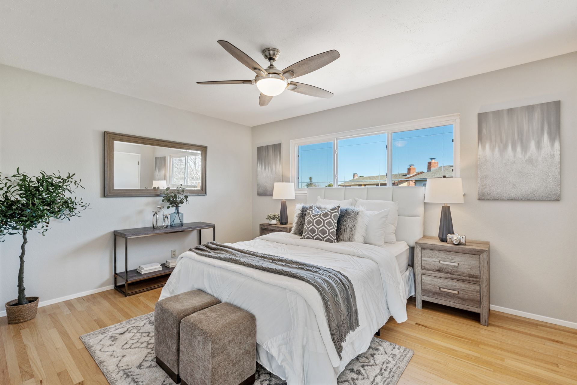 A bedroom with a bed , nightstands , a mirror and a ceiling fan.
