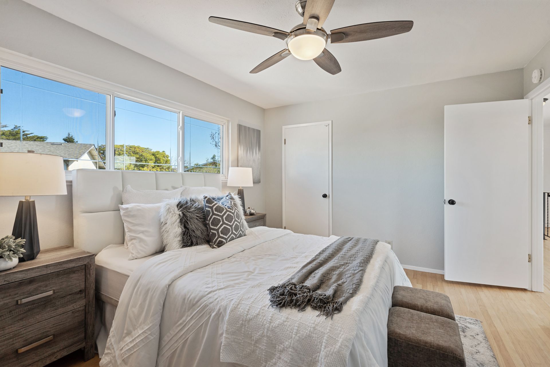 A bedroom with a bed , nightstand , lamp and ceiling fan.