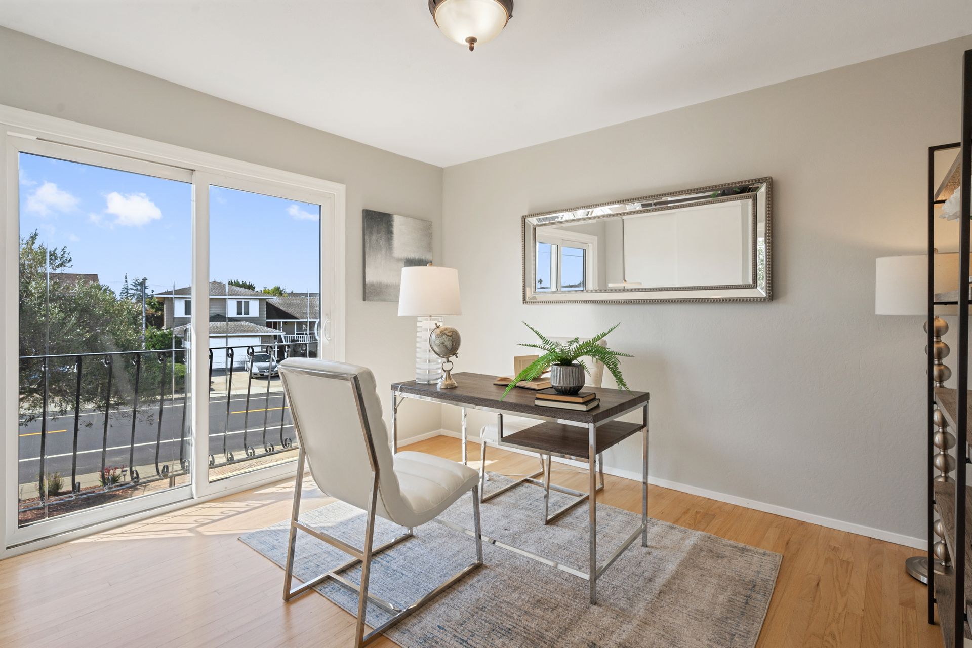 A home office with a desk and chairs and a large window.