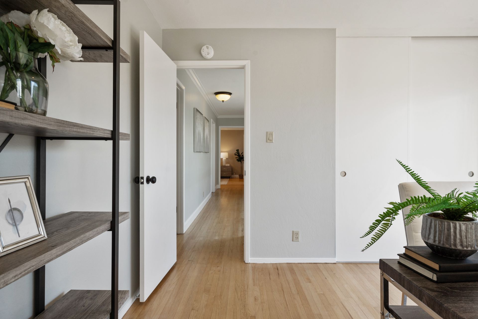 A living room with hardwood floors and a hallway leading to a bedroom.