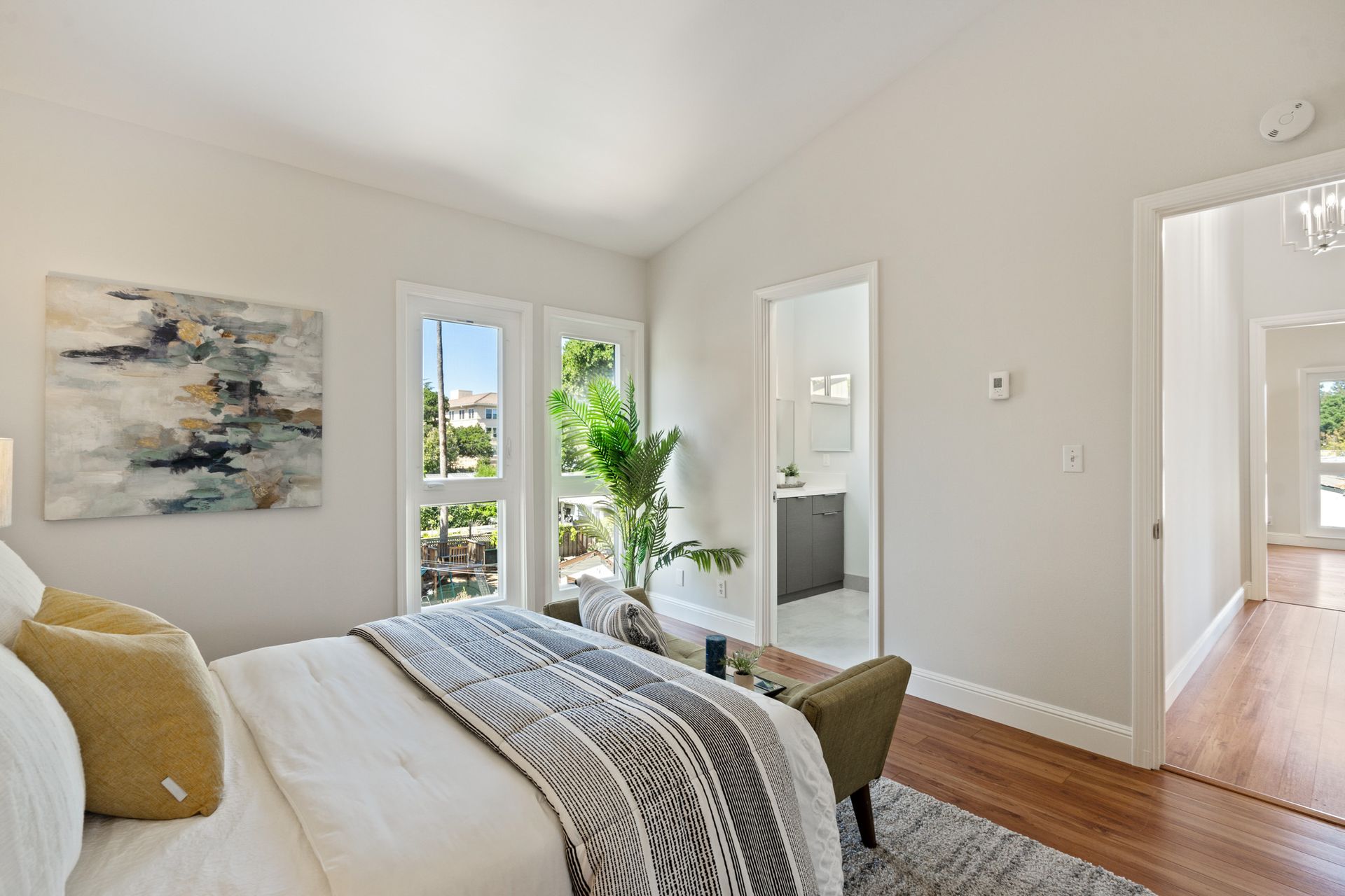A bedroom with a bed , chair , and painting on the wall.