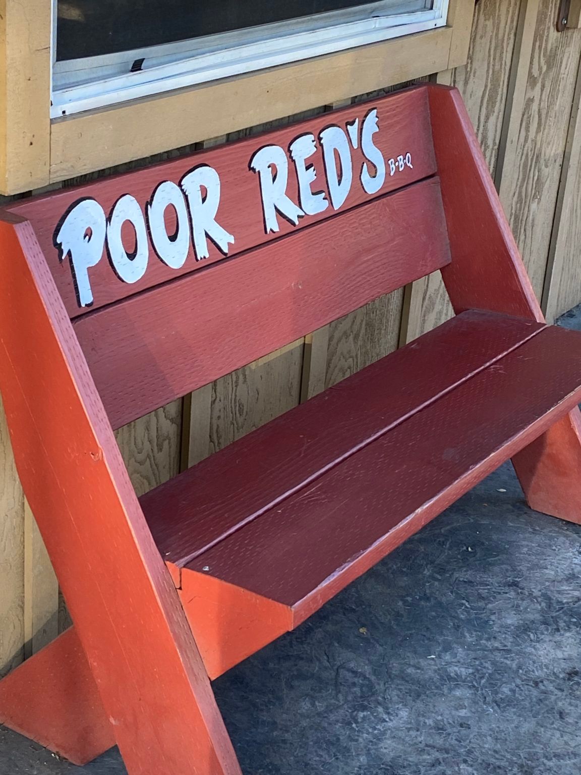 A red bench that says poor red 's on it