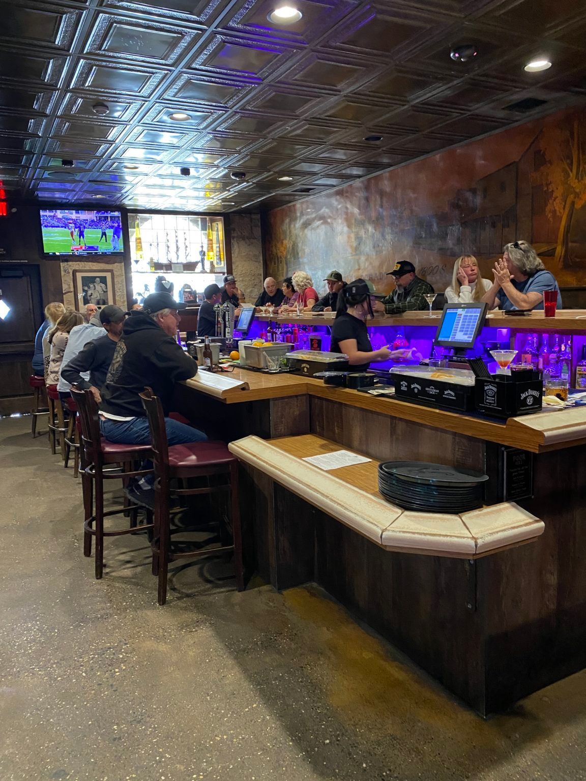 A group of people are sitting at a bar in a restaurant.
