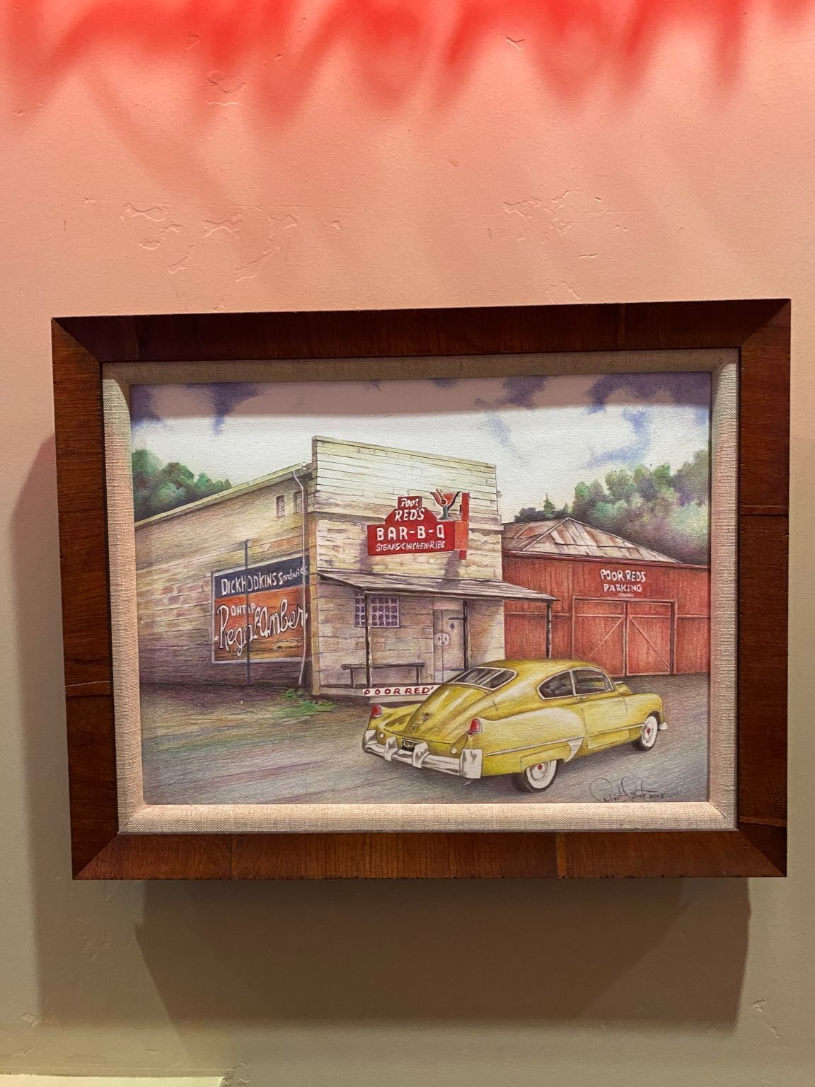 A framed painting of a yellow car parked in front of a building.