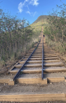 A person is walking up a set of train tracks.