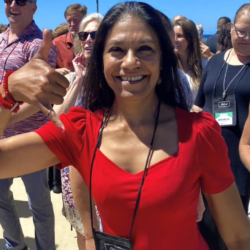A woman in a red shirt is giving a thumbs up