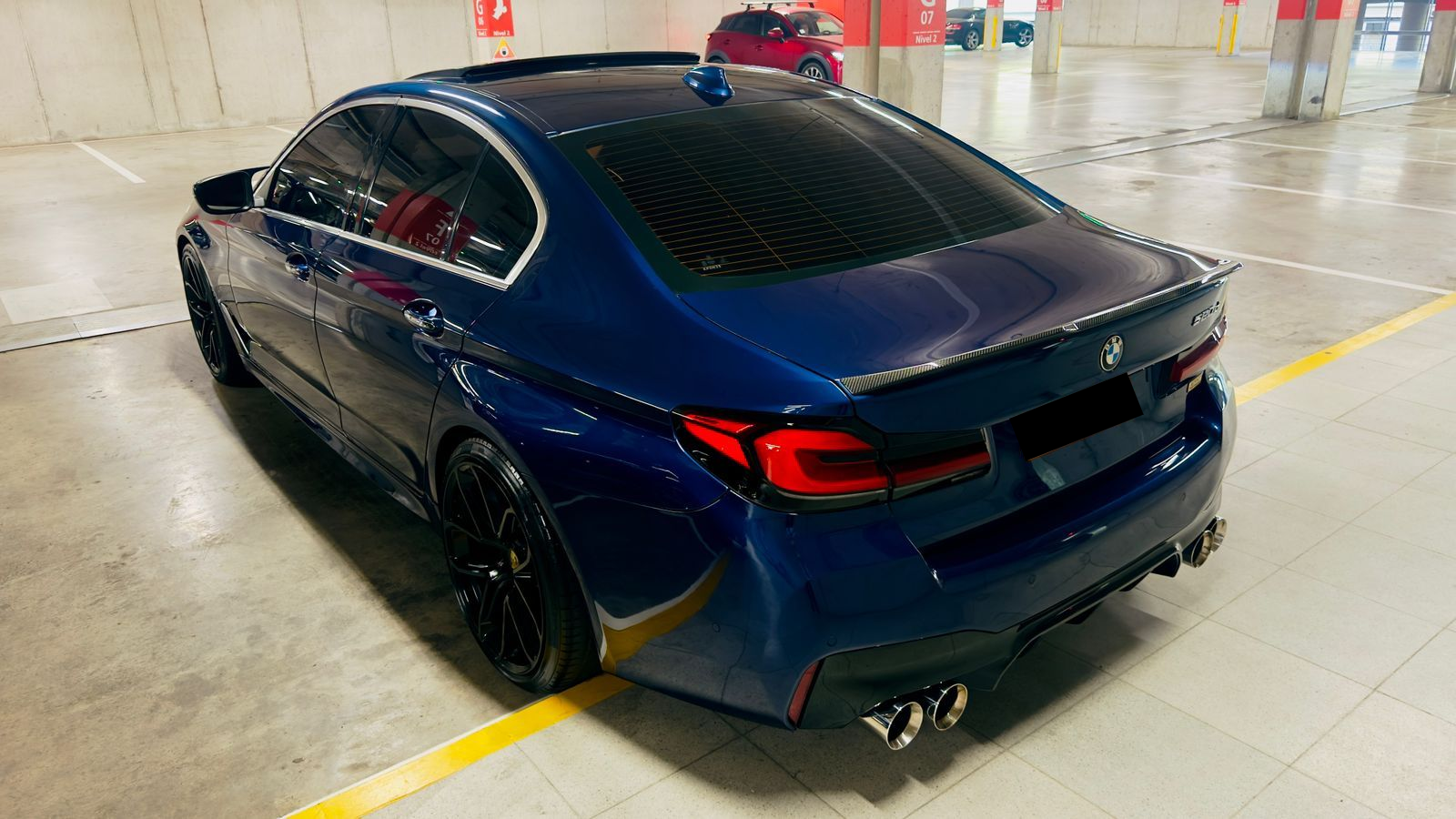 Un sedán BMW azul oscuro estacionado en ángulo en un estacionamiento cubierto de hormigón.
