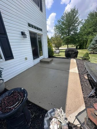 White house patio with concrete walkway, potted plants, and a grill beside a grassy yard under a blue sky