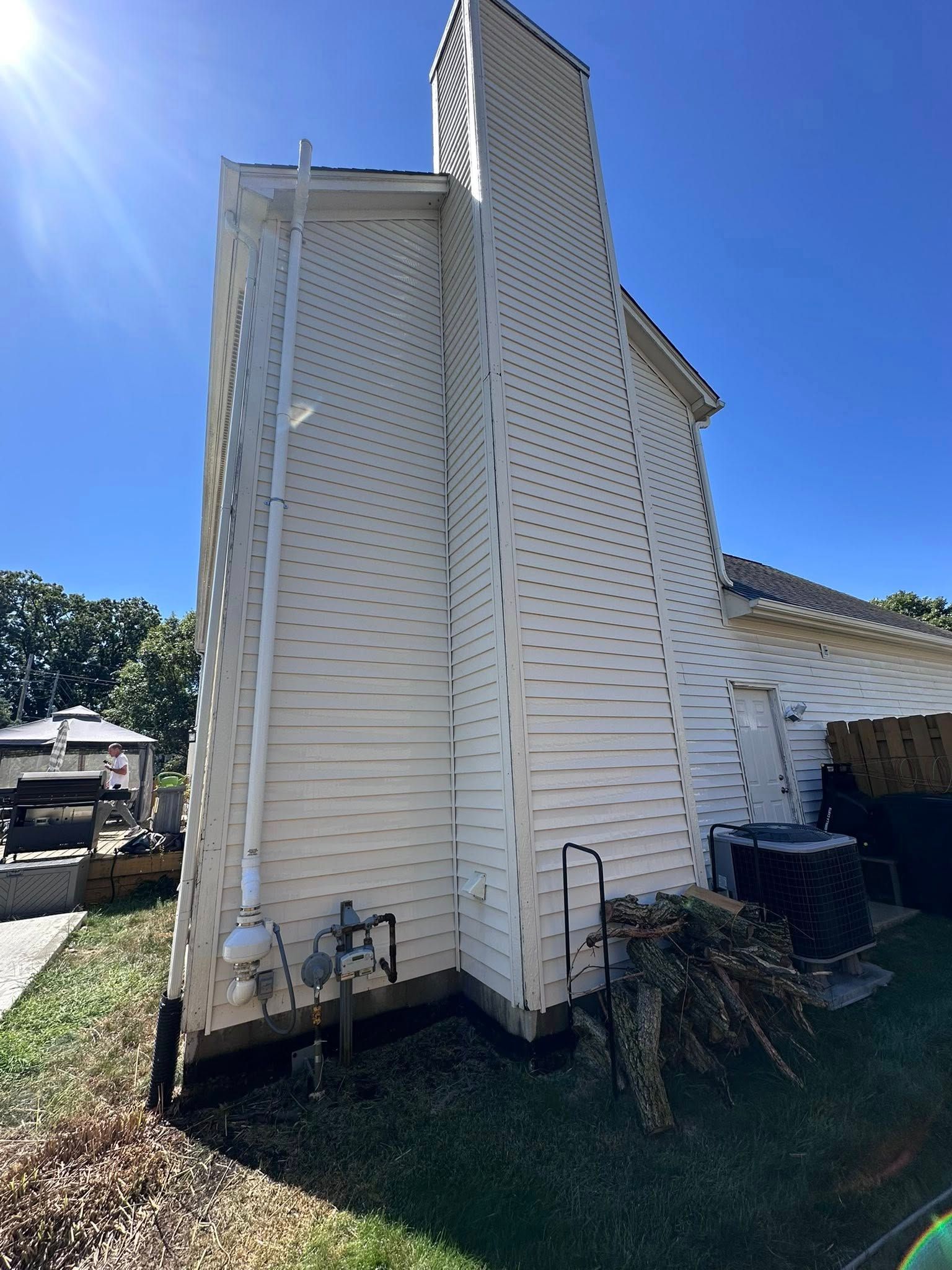 White house exterior with a tall chimney and angled roof under a bright blue sky