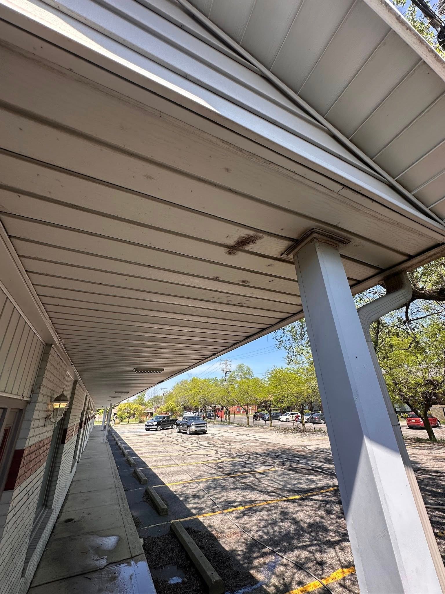 Underneath a covered walkway with a white roof, gray support column, and rocky landscape beyond