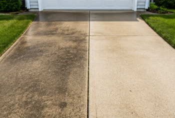 Concrete driveway split between dark stained left side and clean light right side leading to a garage.