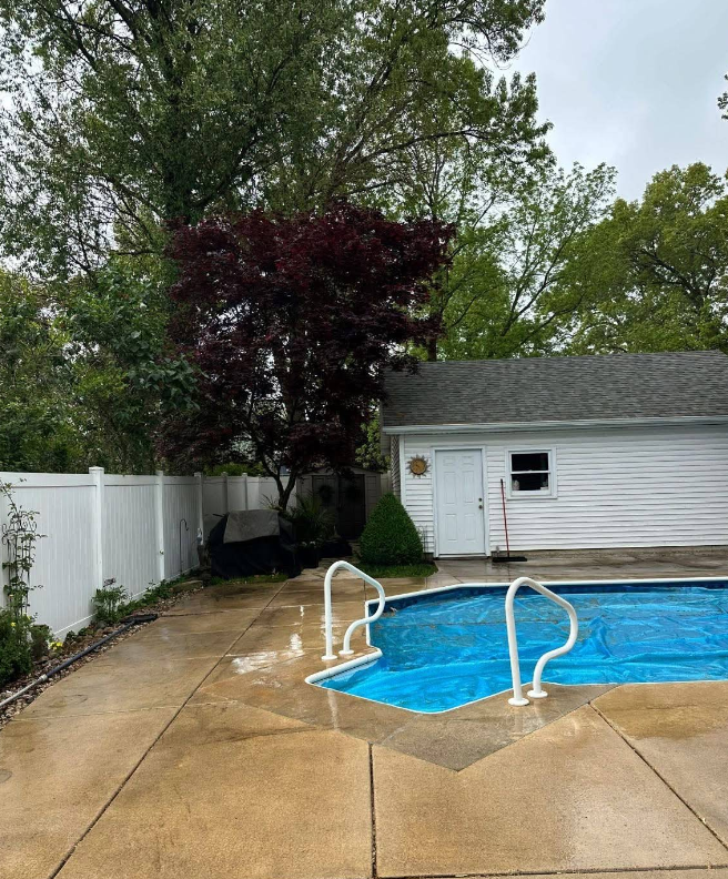 White two-story house with large windows and a person using a hose on the lawn.