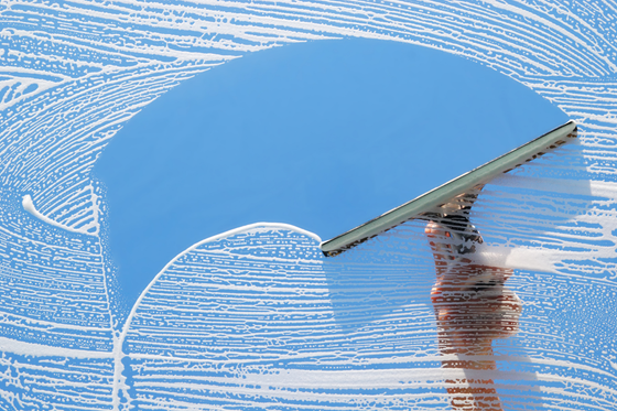 Hand holding a squeegee cleaning a blue circular surface with white streaks on glass